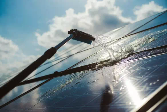 Artisan UpSolaire nettoyant des panneaux photovoltaïques à l’aide d’une brosse et d’eau déminéralisée

