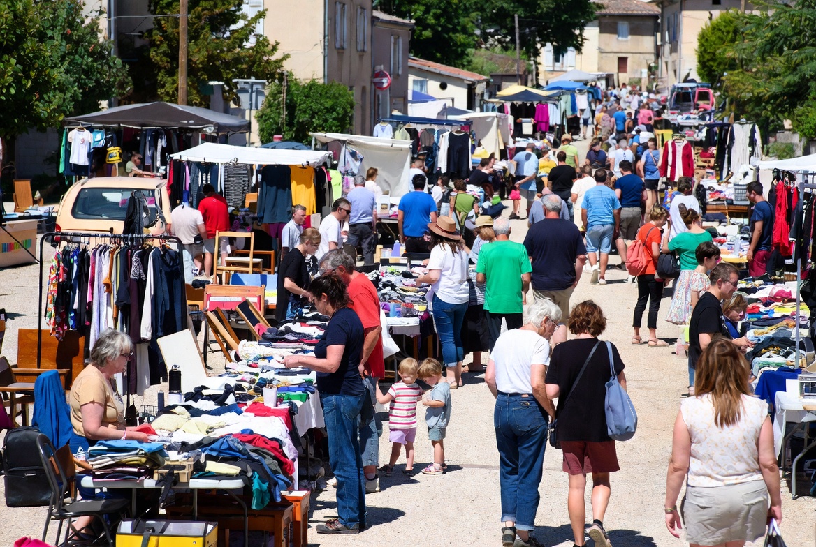 Vide-grenier officiel avec nombreux stands, visiteurs et objets en vente sur la voie publique